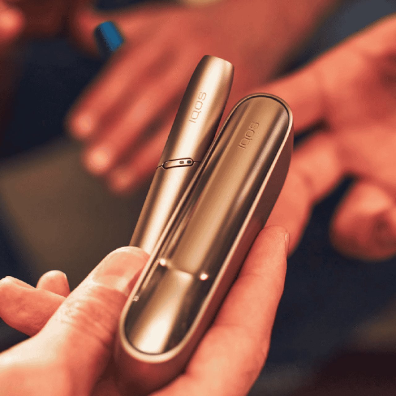 Jemand hält ein goldenes IQOS ILUMA Gerät