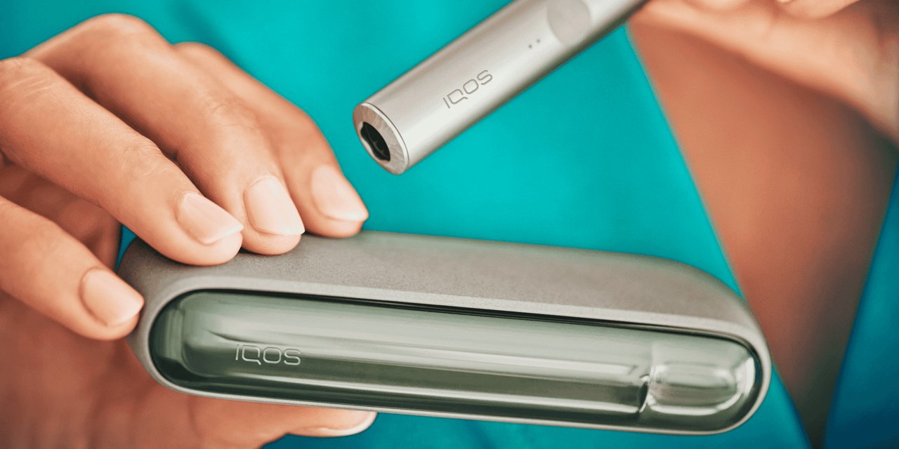 Eine Frau hält ein IQOS ILUMA und einen IQOS ILUMA Holder.