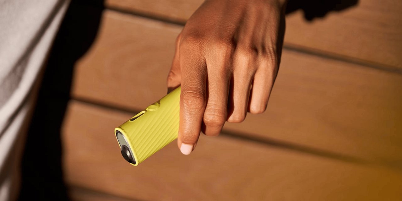 Ein Mann hält ein gelbes IQOS ILUMA One in seiner linken Hand.