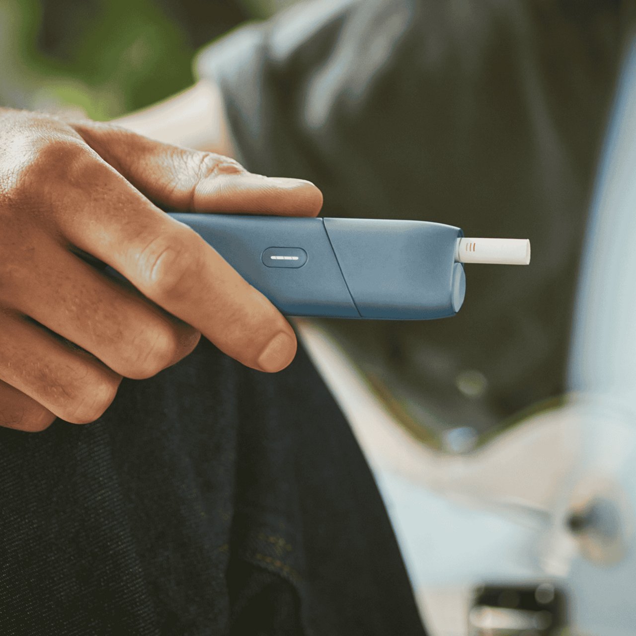 Jemand hält ein blaues IQOS ORIGINALS ONE in der Hand