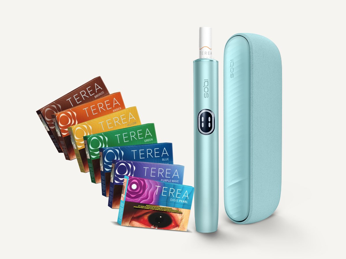 A collection of TEREA heated tobacco packs in various colors arranged in a fan shape, an IQOS holder, and an IQOS charger.