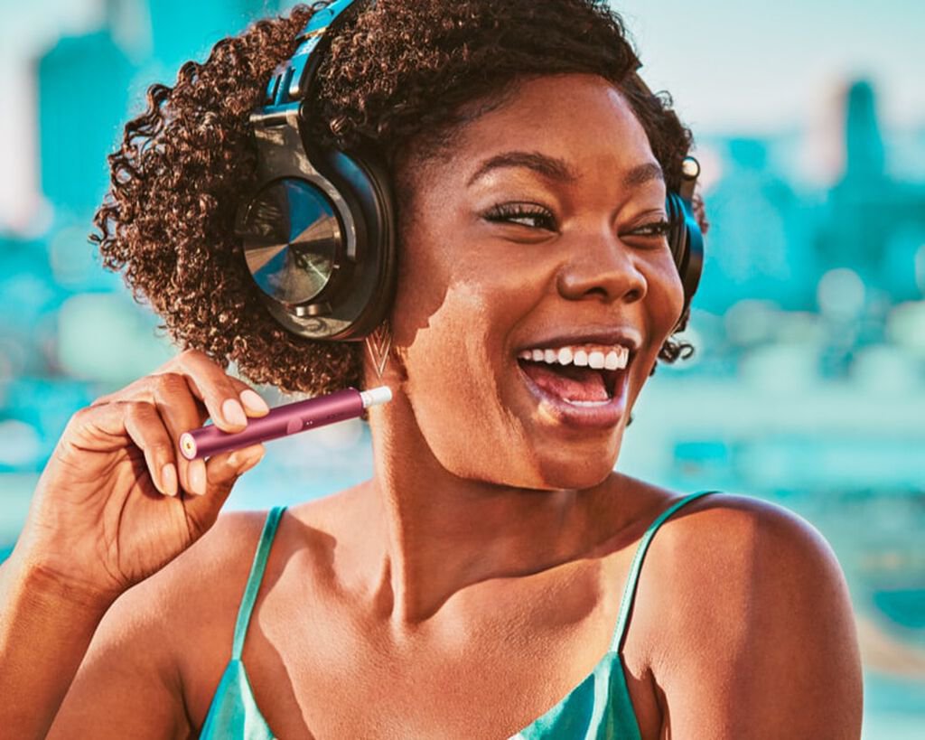 A Jade Green IQOS ILUMA Holder with a ring accessory held by a person with a leather-like full wrap.