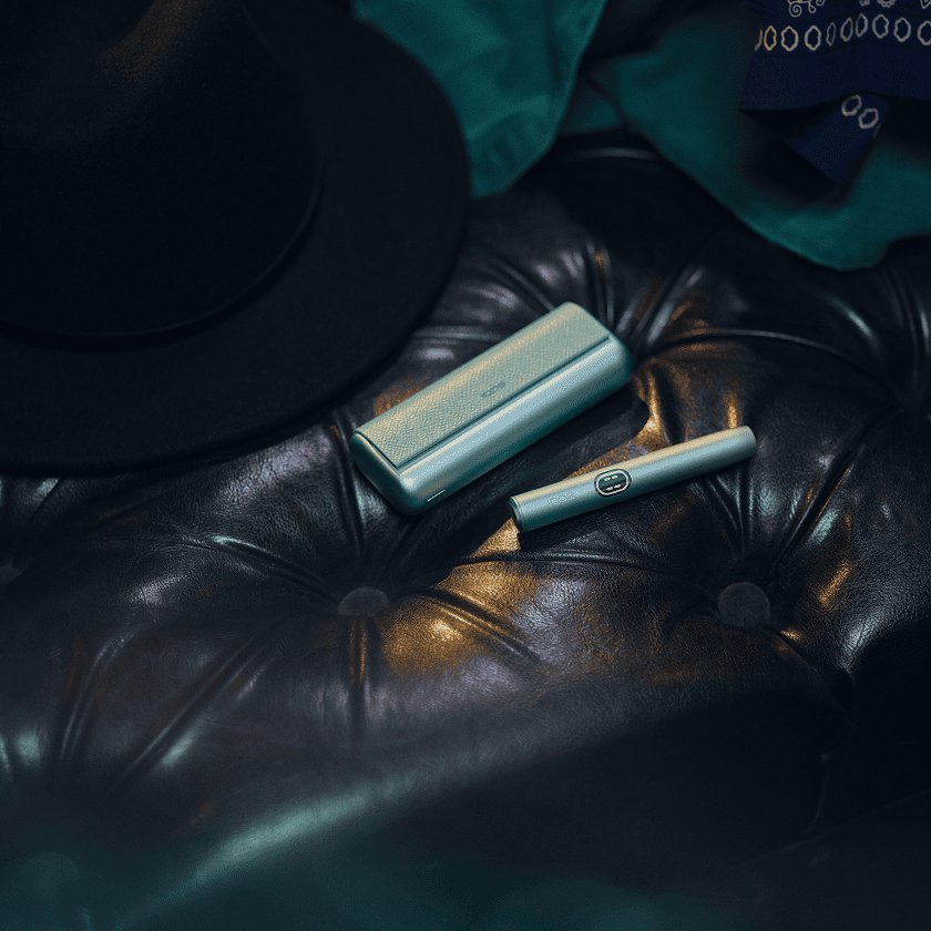 Un IQOS ILUMA i PRIME en color Breeze Blue sobre un sofá