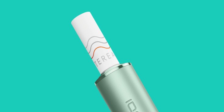Ein jadegrünes IQOS ILUMA PRIME Gerät vor türkisem Hintergrund