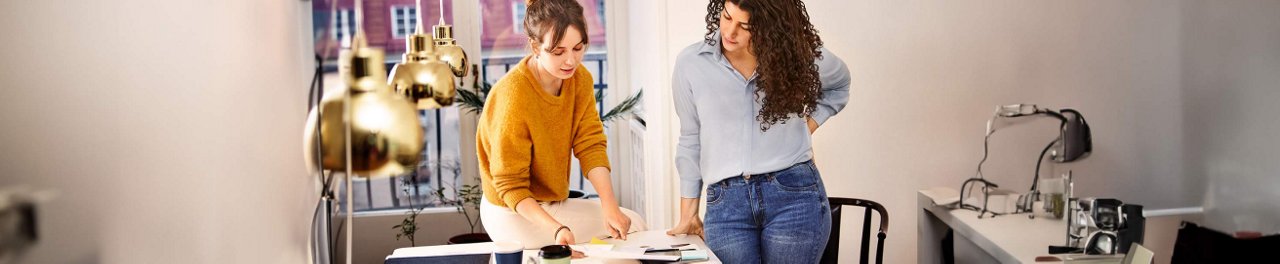 Two women looking at paperwork on a table in the office