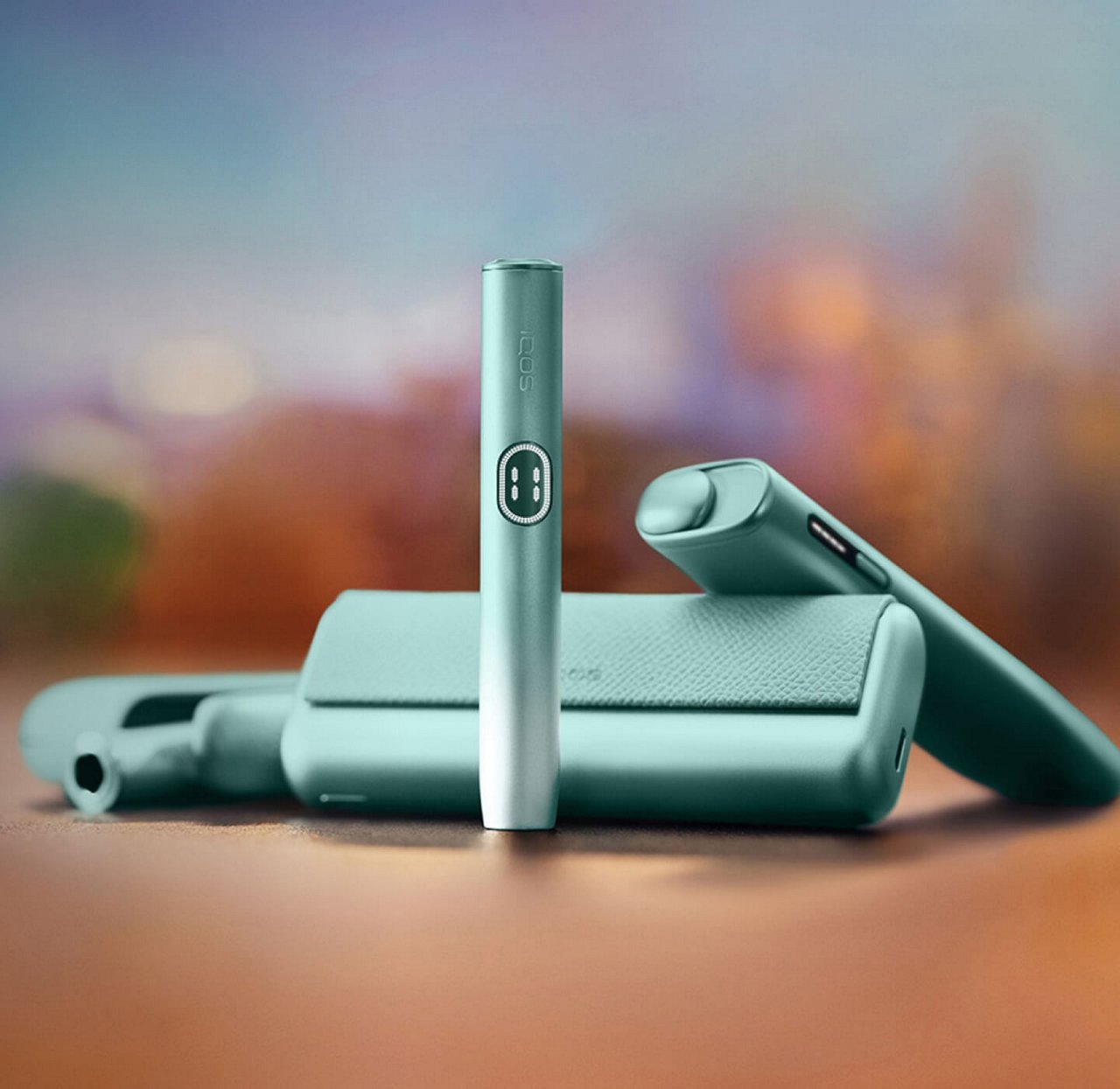 Линейка IQOS ILUMA i цвета Лазурный бриз — IQOS ILUMA i PRIME, IQOS ILUMA i и IQOS ILUMA i ONE на фоне города 