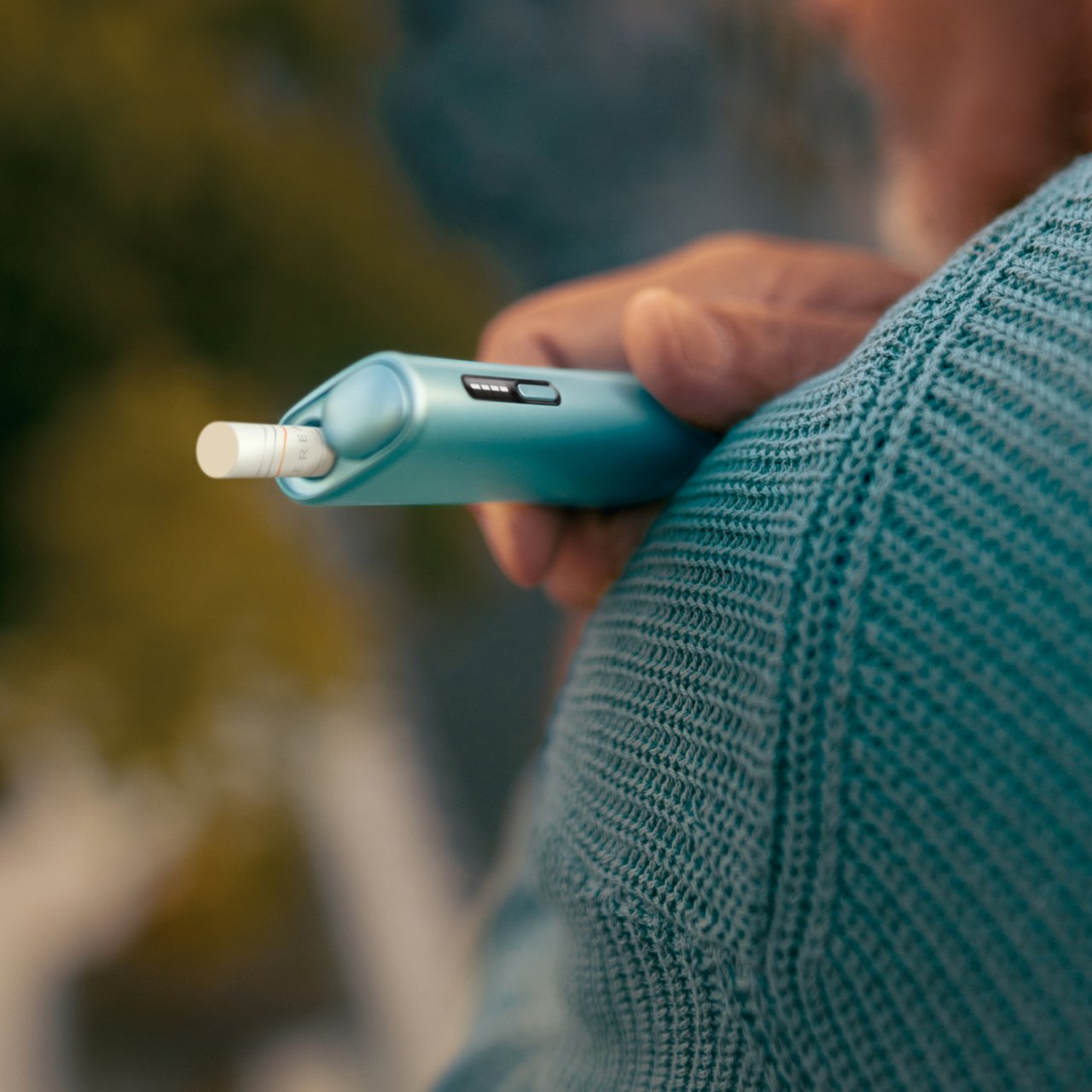 IQOS ILUMA i Tabakerhitzer liegend auf  einem Holztisch.