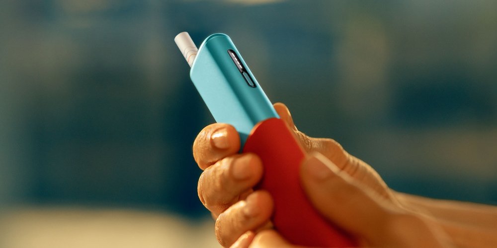 IQOS ILUMA i ONE Tabekerhitzer mit verschiedenen Accessoires dargestellt.