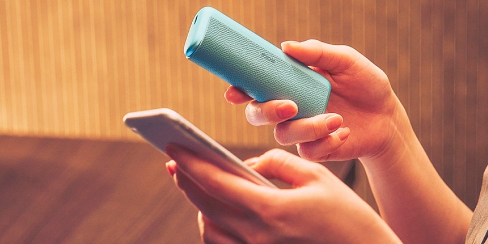 IQOS ILUMA i Tabekerhitzer in der Farbe Breeze Blue dargestellt im Aktualisierungsmodus mit einem Smartphone.