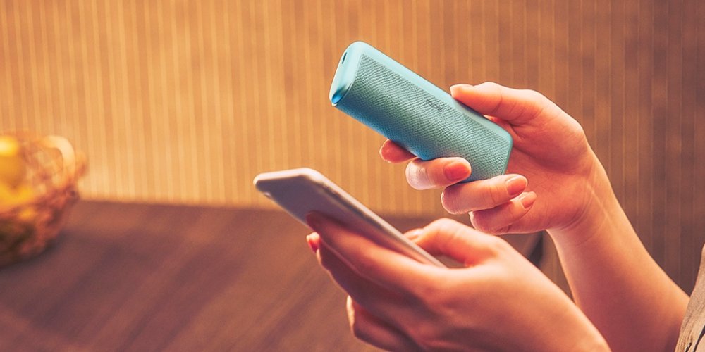 IQOS ILUMA i Tabekerhitzer in der Farbe Breeze Blue dargestellt im Aktualisierungsmodus mit einem Smartphone.