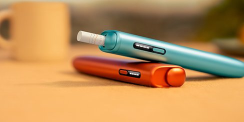 IQOS ILUMA i ONE Tabakerhitzer dargestellt auf einem Holztisch.