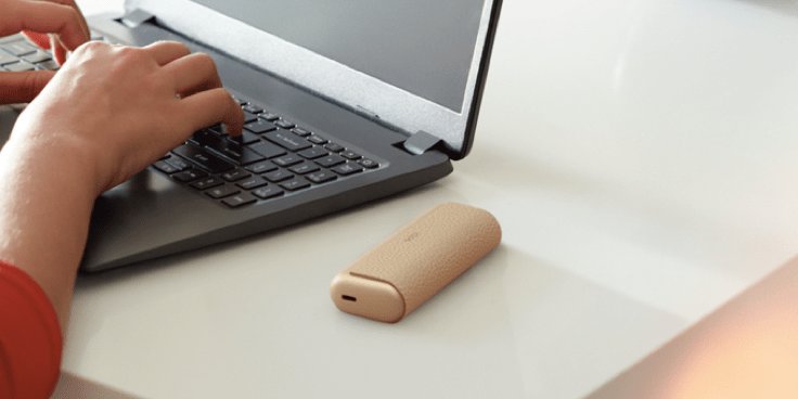Eine Frau bedient einen Laptop und daneben ist ein IQOS ILUMA Prime zu sehen.