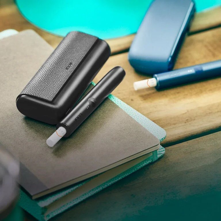 جهاز IQOS باللون الأسود  وجهاز IQOS باللون [لون] مع لفائف موضوعة فيهما.