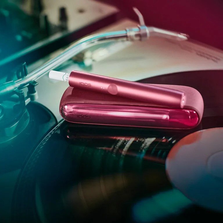 A  [colour] IQOS device with sticks inserted on a record turntable.