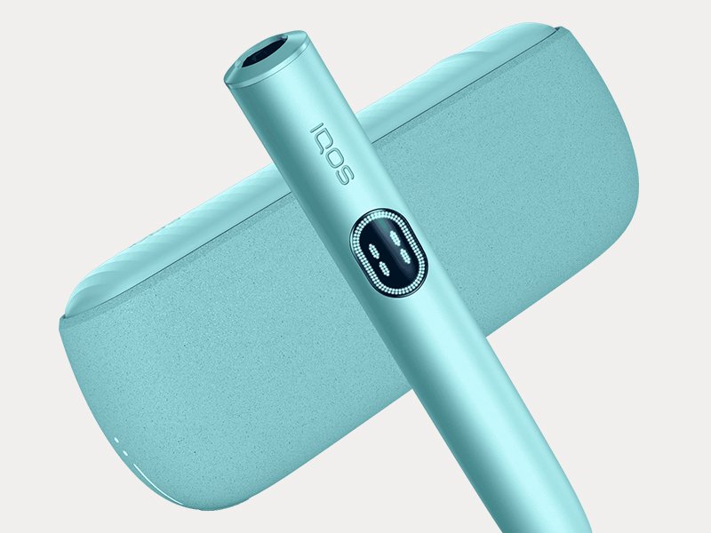 Держатель IQOS ILUMA i PRIME цвета Лазурный бриз перед зарядным устройством на сером фоне