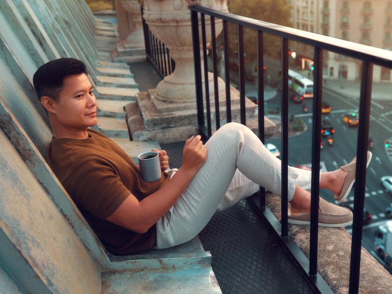 Мужчина сидит на крыше с кофе