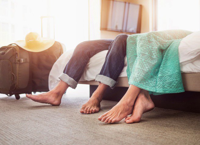 Two people sitting on a bed and their luggage on the floor - close up detail