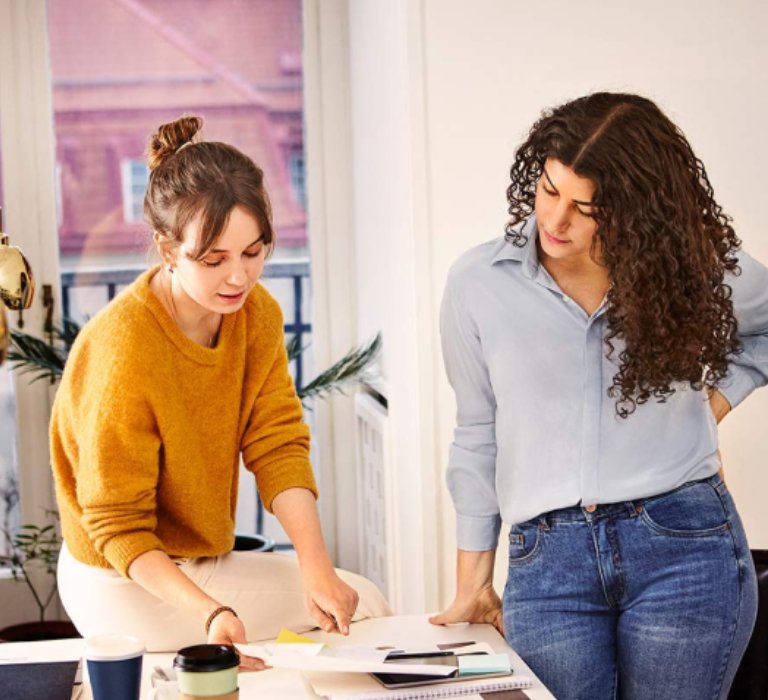 Two women looking at paperwork on a table in the office