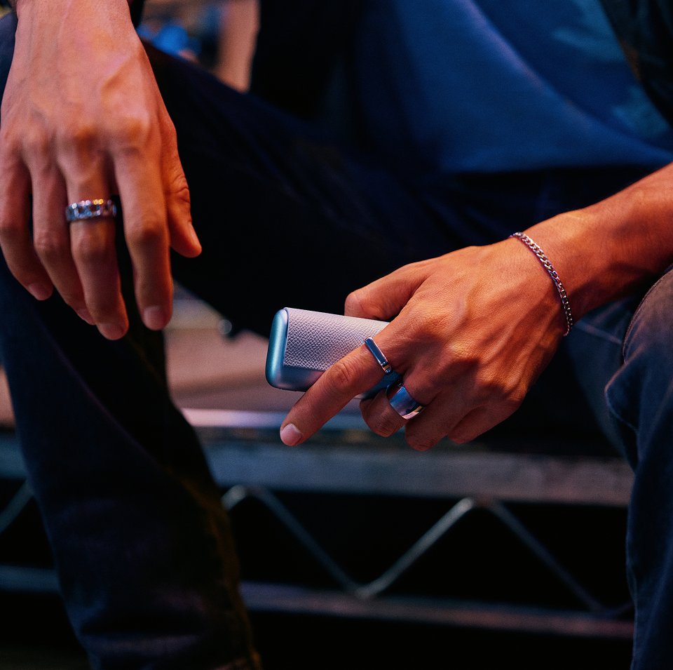 IQOS ILUMA i One color turquesa dentro de una bolsa verde en el asiento del auto.