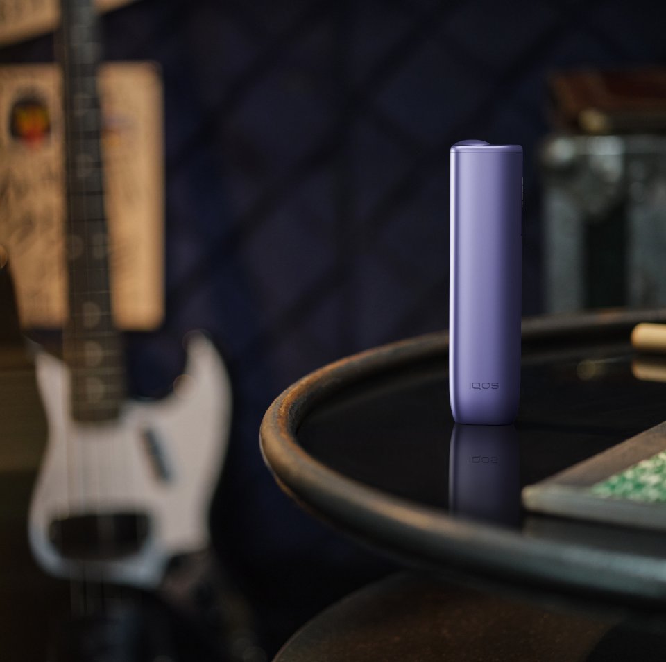 IQOS ILUMA i One color turquesa dentro de una bolsa verde en el asiento del auto.