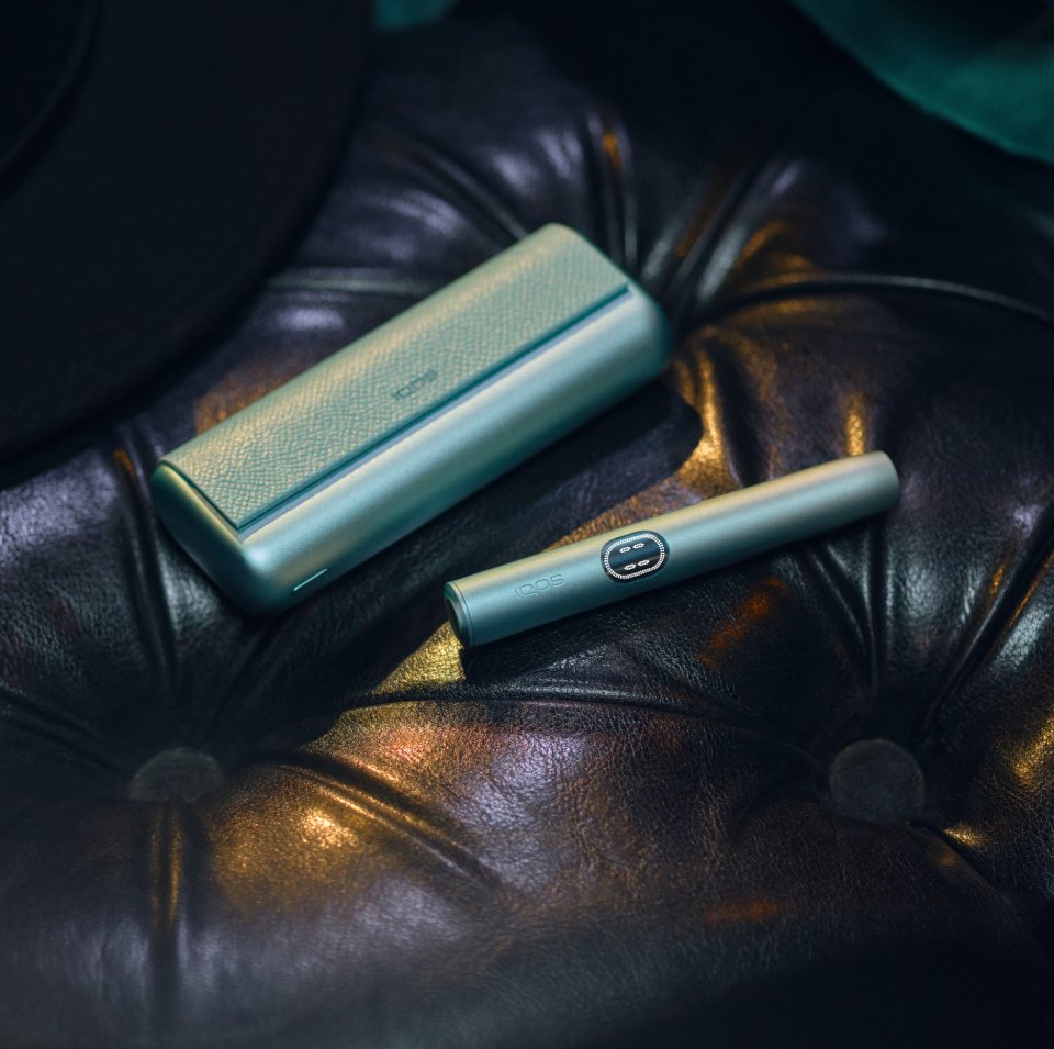 IQOS ILUMA i One color turquesa dentro de una bolsa verde en el asiento del auto.