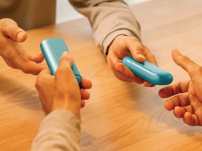 Hands holding and interacting with the IQOS ILUMA i PRIME device for troubleshooting guidance