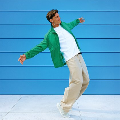 Muz v bielom tricku a zelenej mikine pocuva hudbu