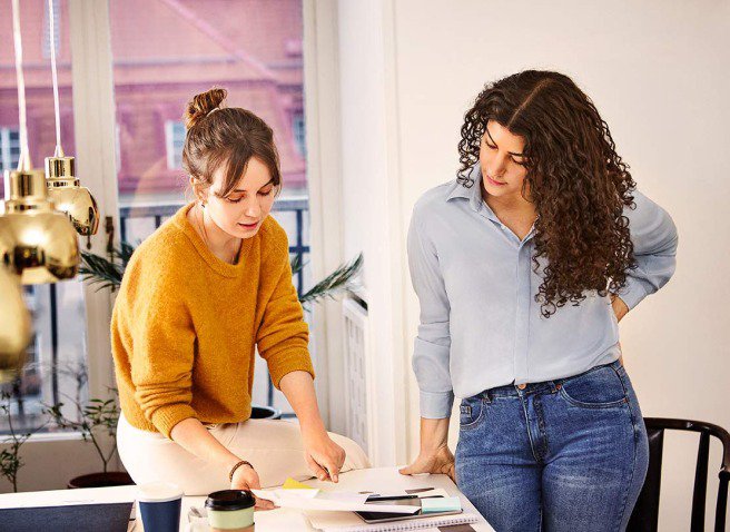 Two women looking at paperwork on a table in the office