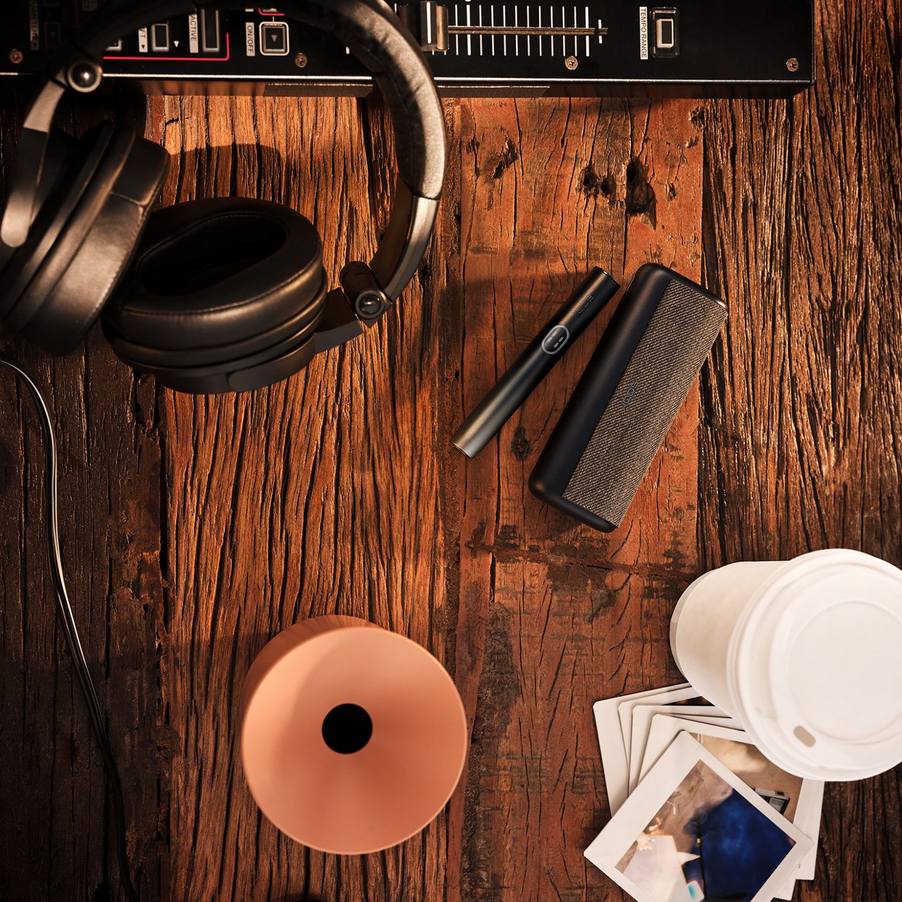 Кара графит түсүндөгү IQOS ILUMA i PRIME түзмөгү столдун үстүндө кофе жана кулакчындар менен