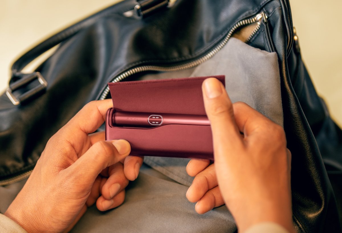 Eine Hand hält eine IQOS ILUMA i Verpackung