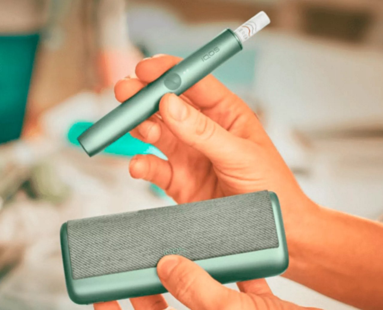 IQOS ILUMA PRIME Holder und Charger werden in den Händen eines Mannes präsentiert.