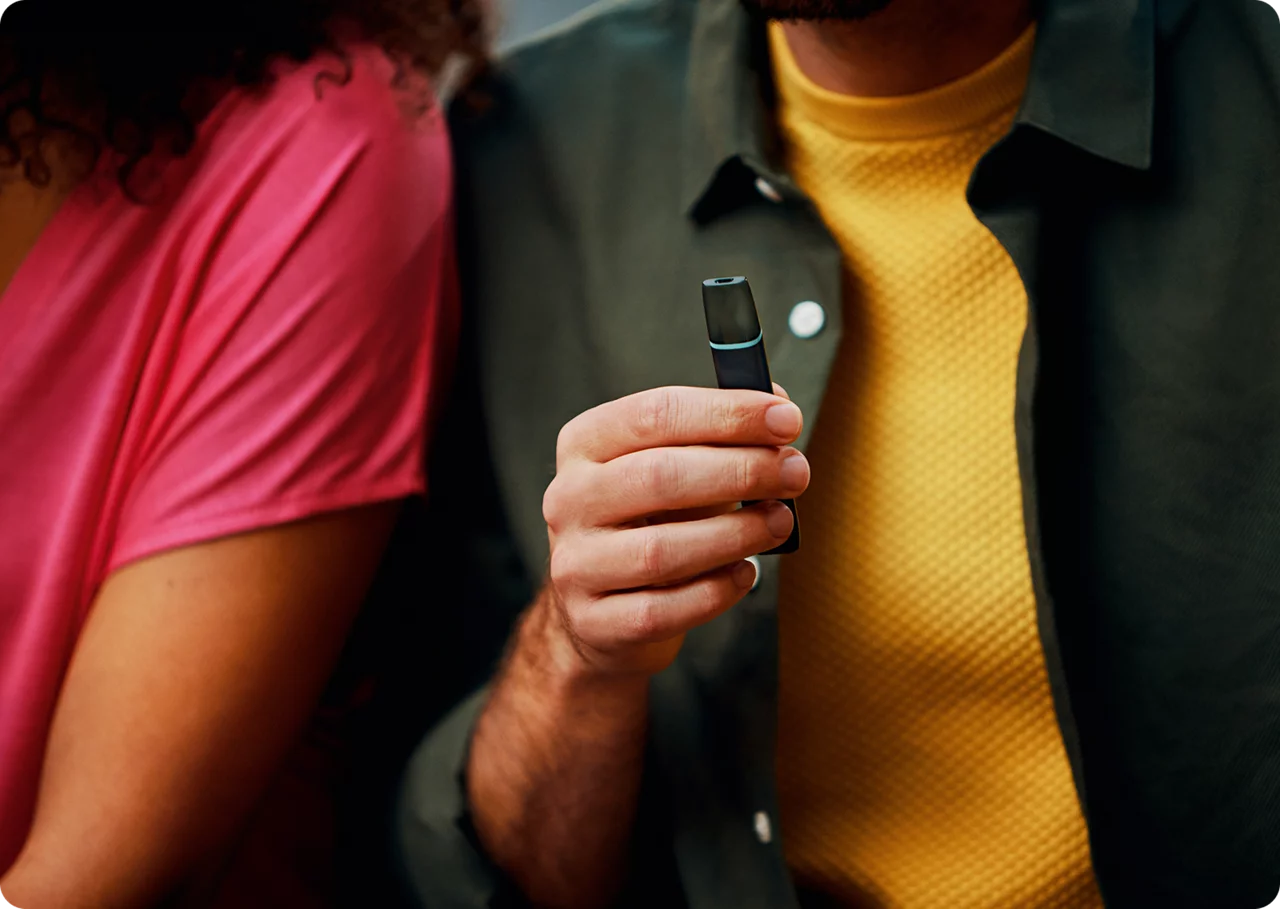 2 Personen, die nebeneinander sitzen und ein VEEV one Gerät in der Hand halten. 