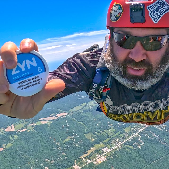 Parachute jumping man, holding a ZYN can. The actions on the photo are performed by professionals or supervised by professionals. Do not attempt