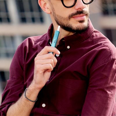A person takes a new IQOS device from its packaging.