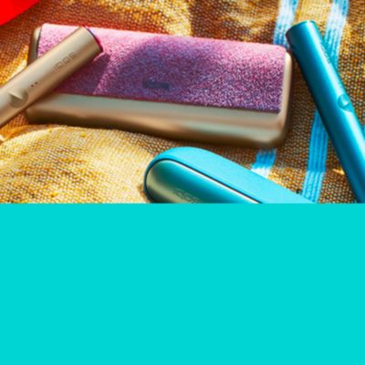 Dve zariadenia IQOS ILUMA v tráve na žltej deke