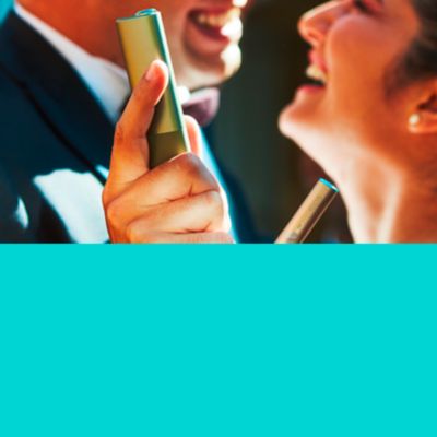 Muž a žena držia v ruke zariadenie IQOS ILUMA a smejú sa