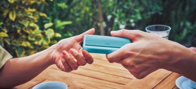 شخص يرتدي الجينز يحمل عبوة جهاز IQOS.