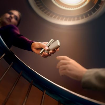 Dos mujeres hablando sobre el programa de referidos del nuevo IQOS Iluma mientras ven un dispositivo.