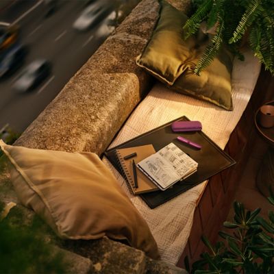 Mujer sosteniendo IQOS Iluma Prime Dorado mientras solicita soporte en su celular.