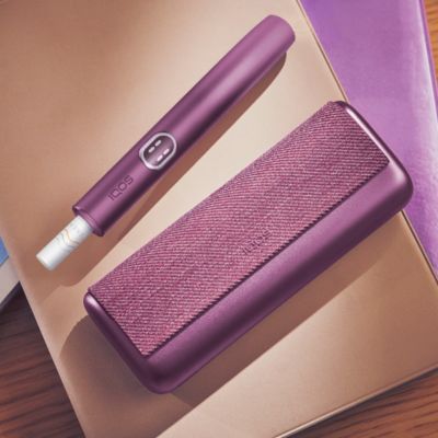 A person takes a new IQOS device from its packaging.