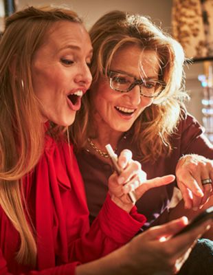 Three joyful people, one holding an IQOS device.
