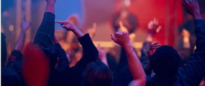 Personas bailando en una fiesta de espaldas a la camara.