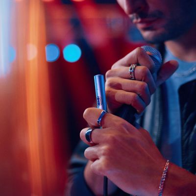 Hombre sosteniendo un IQOS ILUMA i PRIME color Breeze Blue en su mano