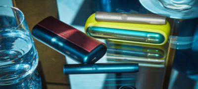 Un par de dispositivos IQOS Iluma con sus accesorios puestos.