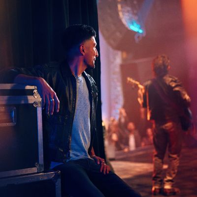 Hombre sentado viendo a un guitarrista tocar