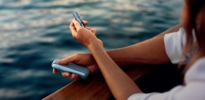 Mujer sosteniendo un IQOS ILUMA mientras mira su computador