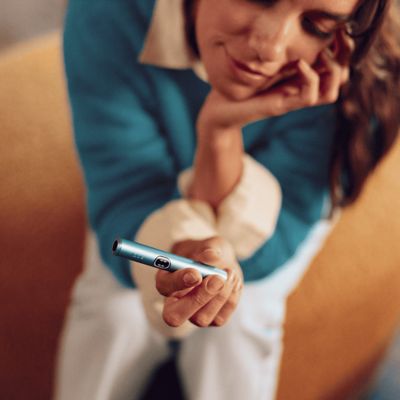 Mujer sosteniendo un IQOS ILUMA i color Breeze Blue