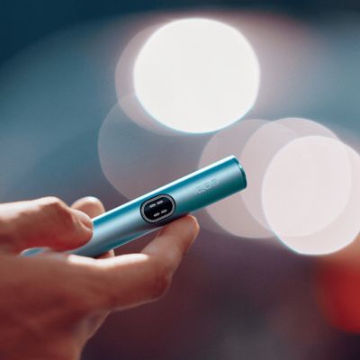 Persona sosteniendo en sus manos un IQOS ILUMA i en color Breeze Blue