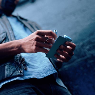 Hombre sosteniendo en sus manos un IQOS ILUMA i PRIME en color Breeze Blue