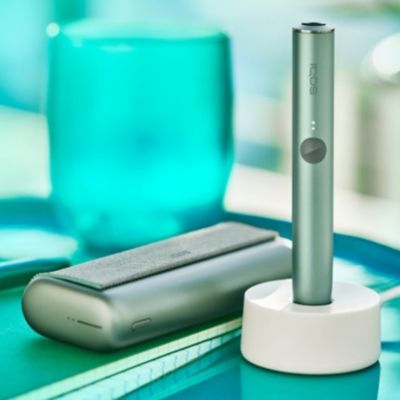 A Jade Green IQOS ILUMA PRIME Holder in a charging station.